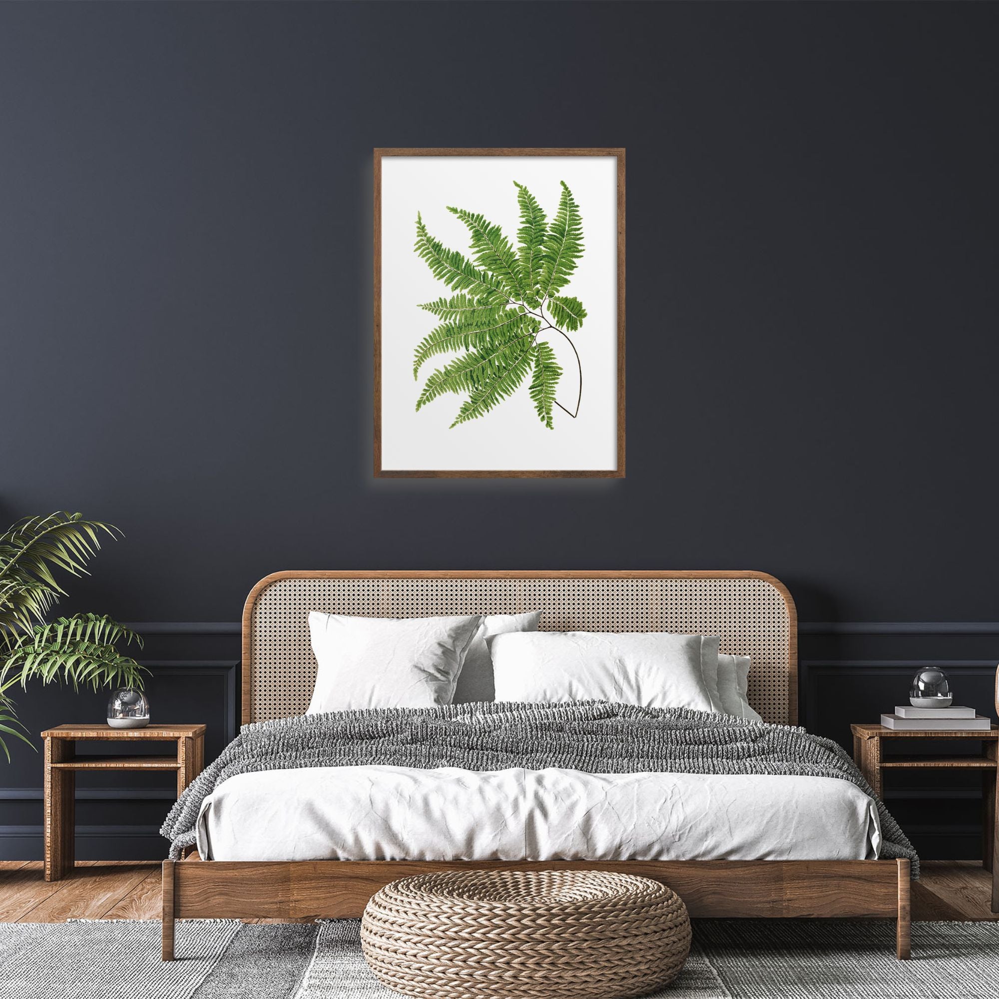 Framed green fern over a bed.