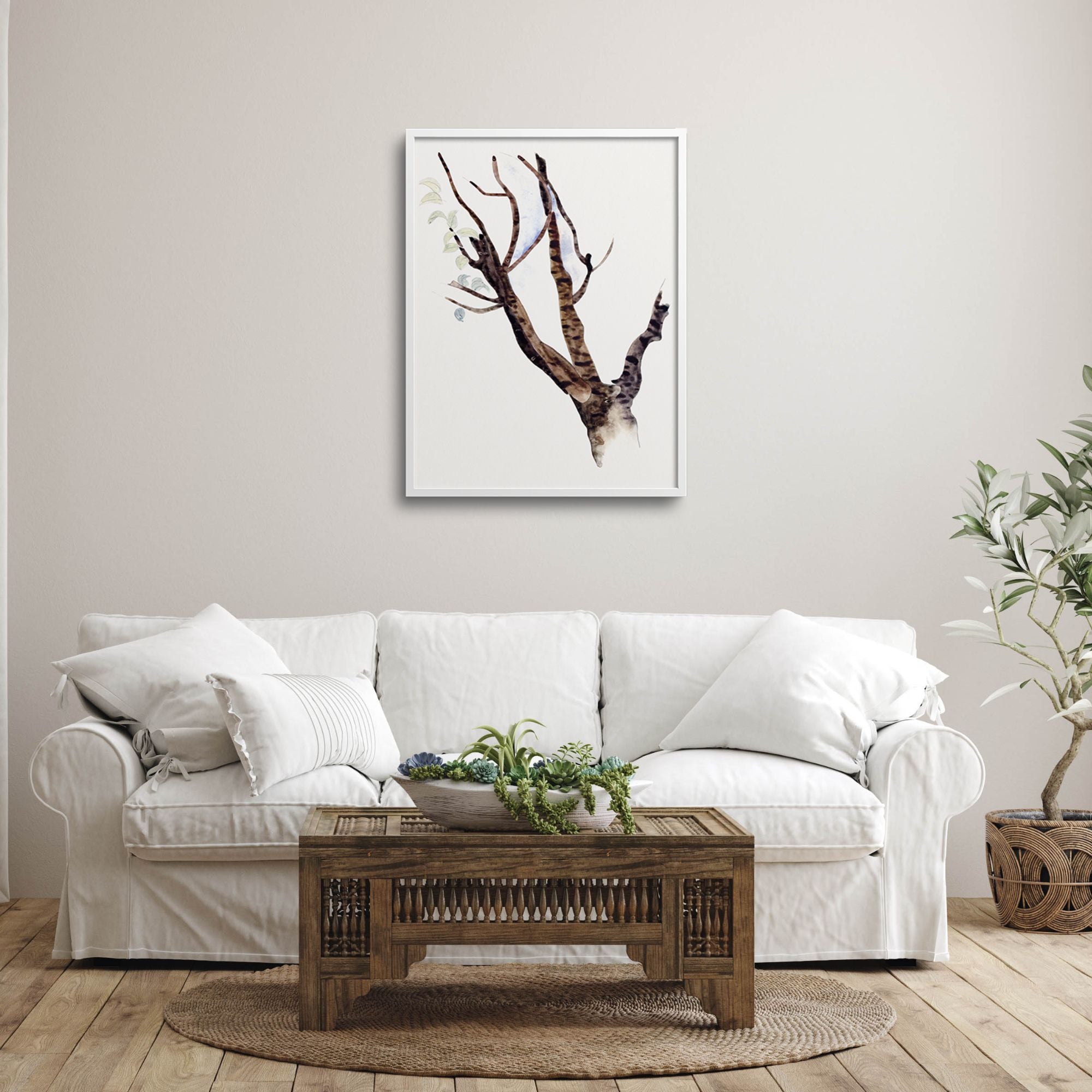 Framed tree form by Charles Demuth over a white living room sofa.