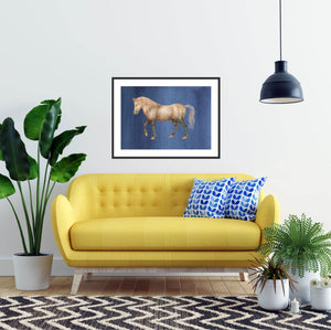 Framed horse over a yellow sofa.